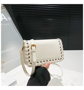 Close-up of cream-colored shoulder bag with cross-woven lace details and gold buckle