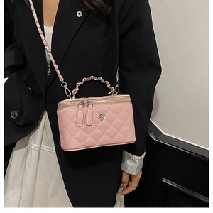 Détail du sac seau rose en cuir matelassé avec fleur argentée et bandoulière chaîne