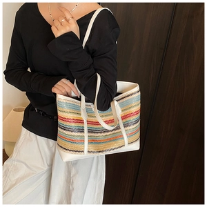 Detail of colorful striped straw tote bag with white leather handles on a model