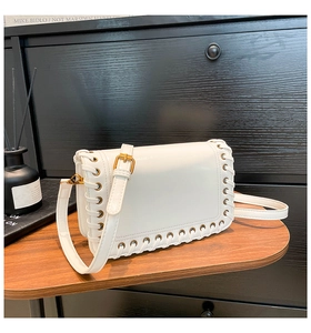 Detail of white woven leather crossbody bag with gold hardware and laced edge design