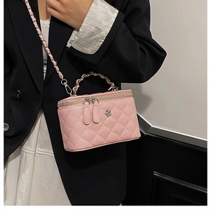 Sac seau matelassé rose avec bandoulière chaîne et détail fleur sur tenue noire élégante