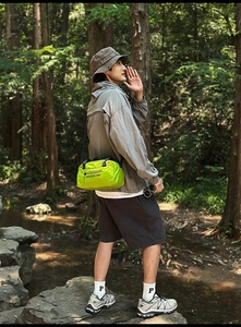 Outdoor scene showing the neon green nylon crossbody bag with durable sports straps