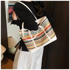 Detailed view of colorful woven straw tote bag with white leather straps and trim