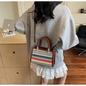 Detailed back view of model carrying a colorful woven tote bag with brown leather straps