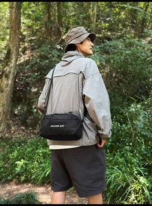 Close-up of black nylon crossbody bag with SHILAIEN-ART logo in an outdoor setting