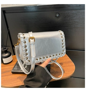 Detail of silver metallic crossbody bag with unique metal ring eyelet weaving edge