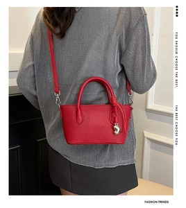 Détail du sac seau en cuir rouge avec pendentif cœur porté en sac bandoulière