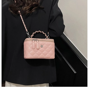 Détail d'un sac vanity rose matelassé avec fermoir fleur et bandoulière en chaîne