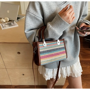 Detailed shot of multi-color woven handbag with brown leather trim and silver metal hardware