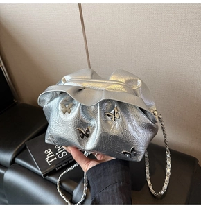 Detailed view of silver metallic pleated bucket bag with butterfly hardware charms