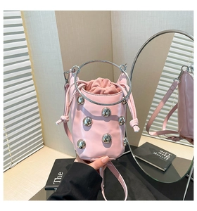 Rosa Eimertasche mit Metallic-Nieten und silbernen Rundgriffen in Makro-Detailaufnahme