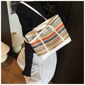 Detailed close-up of a large colorful striped straw tote bag with white leather piping details