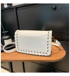 Detail of white leather crossbody bag with woven edges and vintage brass metal buckle