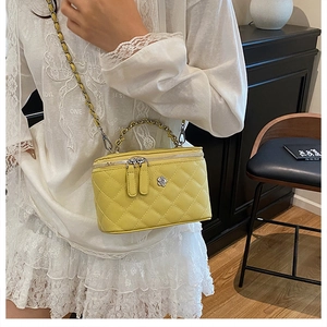 Détail d'un sac seau jaune matelassé avec poignée en métal argenté et bandoulière chaîne
