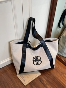 Minimalist beige canvas tote bag with black leather straps and embroidered logo