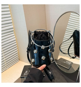 Detailaufnahme der schwarzen Lack-Eimertasche mit Silbernieten und Metallring-Griff