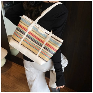 Close-up of multicolored striped woven tote with white leather trim and brand logo