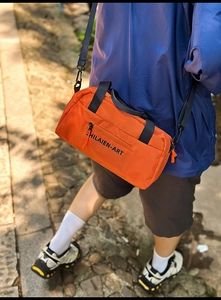 Orange nylon sports bag with waffle texture and adjustable black crossbody strap