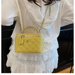 Détail du sac seau jaune matelassé avec fleur en métal et bandoulière en chaîne