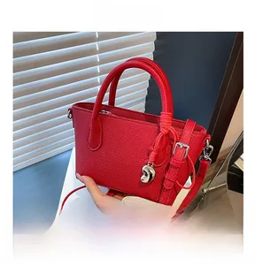 Détail du sac seau rouge en cuir grainé avec breloque argentée et bandoulière