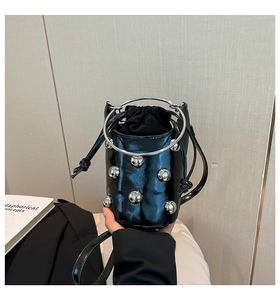 Detail der glänzenden schwarzen Lackleder-Beuteltasche mit silbernen Metallkugeln und Ringgriff