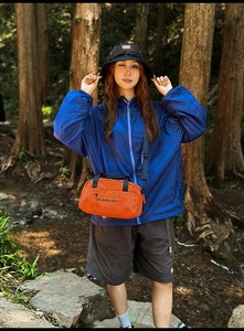 Outdoor leisure outfit featuring a bright orange nylon crossbody bag in a forest setting