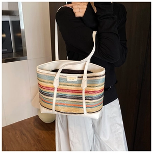 Detail of multi-color woven straw tote with white leather handles and brand logo tag