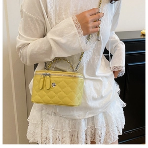 Gros plan sur un sac seau jaune matelassé avec poignée chaîne et détails floraux