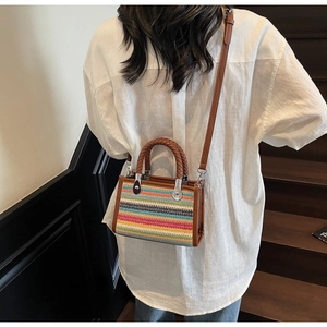 Detail view of the colorful woven pattern and brown handles on this bohemian style bag