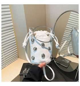Detail der weißen Leder-Beuteltasche mit silbernen Nieten und rundem Metallgriff