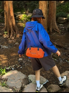 Orange nylon sports crossbody bag shown in outdoor setting with waterproof material details
