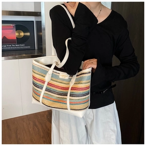 Detail of colorful striped straw tote bag featuring leather trim and brand logo patch
