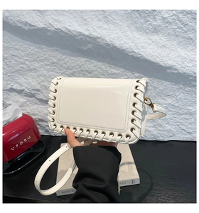 Close-up of white leather square bag featuring distinctive woven rope edges and metal buckle