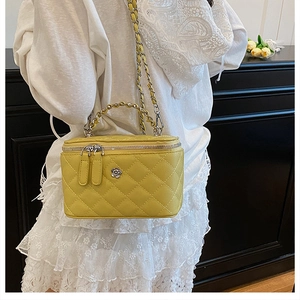 Détail du sac seau jaune matelassé avec fermoir fleur en métal et bandoulière en chaîne