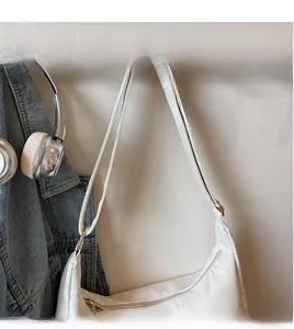 Detailed view of white crescent bag with golden zipper and adjustable shoulder strap