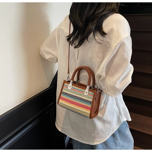 Detail of multi-colored striped woven handbag with brown leather handles and strap