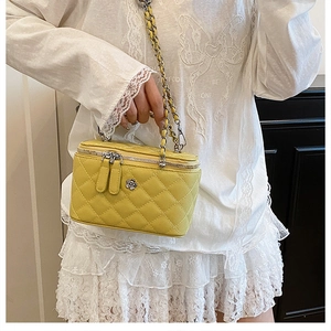 Détail du sac seau jaune matelassé avec logo fleur argenté et bandoulière en chaîne