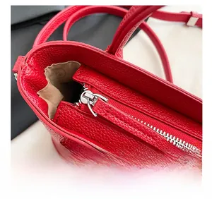 Détail de la fermeture éclair métallique et de la texture en cuir grainé du sac seau rouge