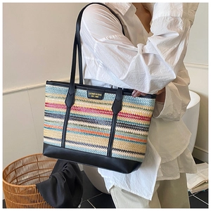 Detail of colorful straw woven tote bag with black leather trim and metal brand logo