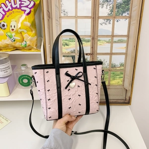 Vue détaillée du sac seau en nylon rose avec nœud noir et pendentif en cœur