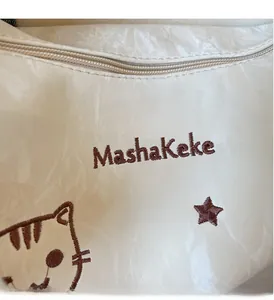 Macro view of creamy white tote bag featuring pleated texture and MashaKeke embroidery
