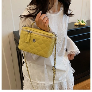 Vue détaillée du sac seau jaune matelassé avec logo fleur et bandoulière en chaîne cuir
