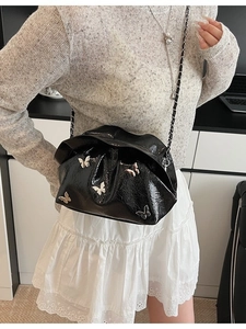 Fashionable black patent leather bucket bag with silver butterfly charms and chain strap