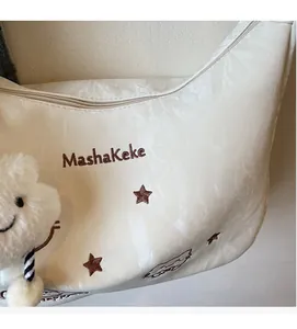 Detail of cream shoulder bag with Mashakeke embroidery and plush star charm