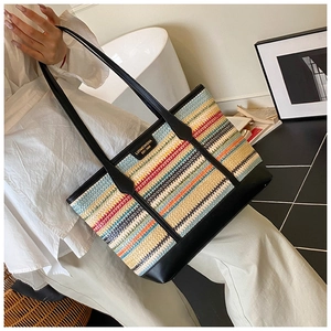Detail of multi-color woven tote bag featuring black leather straps and golden brand plate