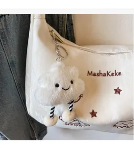 Detail of cute white plush cloud charm accessory with striped legs on a shoulder bag