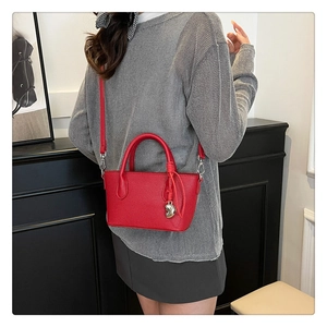 Gros plan du sac seau rouge à texture litchi avec pendentif cœur sur un modèle