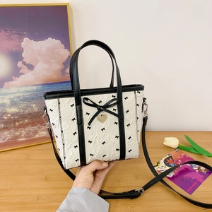 Détails du sac seau en nylon blanc avec motifs de nœuds noirs et pendentif cœur doré
