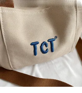 Détail de la texture en toile avec logo TCT brodé sur un sac fourre-tout minimaliste