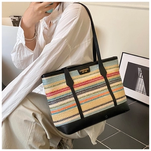 Detailed view of colorful woven tote bag with black leather straps on model shoulder